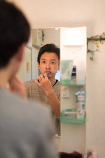 鏡越しに歯を磨く男性｜五反田歯科